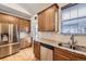 Well-lit kitchen boasts stainless steel appliances, granite counters, wood cabinets, and double sink at 1945 Basil St, Strasburg, CO 80136