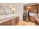 Bright kitchen features stainless steel refrigerator, granite countertops, wood cabinets, and wood floors at 1945 Basil St, Strasburg, CO 80136