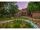 Backyard featuring multi-level wood deck with stairs, garden beds, mature trees, and lush lawn at 9832 High St, Thornton, CO 80229