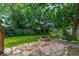 Landscaped backyard features a stone firepit area with mature trees and garden beds at 9832 High St, Thornton, CO 80229