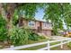 Split level home surrounded by trees, featuring an attached garage, and white fence at 9832 High St, Thornton, CO 80229