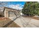 A single car garage with brick accents and a concrete driveway, shaded by a mature tree, and topped by a clear blue sky at 5761 W 71St Ave, Arvada, CO 80003