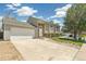 View of home with attached two car garage featuring stone accents and mature landscaping at 5886 S Nepal Way, Centennial, CO 80015