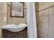 Close-up of bathroom sink, vanity, mirror, shower curtain, and tiled walls at 12022 W Dakota Dr, Lakewood, CO 80228