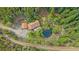 Aerial view of a charming mountain home with a pond and surrounded by lush green trees at 80 Castlewood Ct, Evergreen, CO 80439