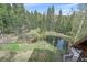 Stunning aerial view of a backyard featuring a pond, a fire pit, and evergreen trees at 80 Castlewood Ct, Evergreen, CO 80439