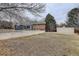 Expansive backyard featuring mature trees, a concrete patio, and a sturdy retaining wall for added privacy at 6389 S Ponds Way, Littleton, CO 80123