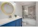 Renovated bathroom featuring blue vanity, decorative mirror, and tiled shower at 6389 S Ponds Way, Littleton, CO 80123