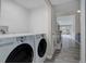 Laundry room with modern washer and dryer, leading to bright hallway and living area at 6389 S Ponds Way, Littleton, CO 80123