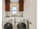 Laundry room featuring white washer and dryer, dark wood cabinets, and a window at 17040 Galapago Ct, Broomfield, CO 80023