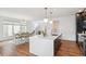 Bright, open kitchen features a marble-top island with seating, modern lighting, and wood floors at 2339 W 66Th Ave, Denver, CO 80221
