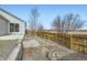 The fenced backyard features a stone retaining wall, gravel, and a fire pit, creating an inviting outdoor retreat at 4296 Clover Ln, Brighton, CO 80601