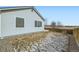 Side view of the home and backyard with partial snow, a wood fence, and gravel, enhancing the property's appeal at 4296 Clover Ln, Brighton, CO 80601