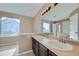 Bright bathroom featuring a double sink vanity, and a large mirror with decorative lighting at 4296 Clover Ln, Brighton, CO 80601