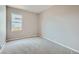 Empty bedroom with neutral carpet and paint, showcasing the window and baseboard trim at 4296 Clover Ln, Brighton, CO 80601