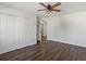 Bright bedroom with dark wood floor, ceiling fan, and white closet doors at 12695 Wolff St, Broomfield, CO 80020