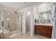 Clean bathroom with a glass-enclosed shower and vanity with dark wood cabinets at 15562 E 109Th Ave, Commerce City, CO 80022