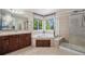 Bright bathroom featuring a corner tub, glass shower, and dual windows at 15562 E 109Th Ave, Commerce City, CO 80022