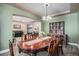 Dining room with a long wooden table, chandelier, built-in display cabinet, and open access to a living area at 15562 E 109Th Ave, Commerce City, CO 80022