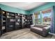 Home office space with built-in shelving, neutral couch, wood floors, and natural light from two windows at 15562 E 109Th Ave, Commerce City, CO 80022