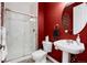 Cozy bathroom featuring a pedestal sink, toilet, and a glass-enclosed shower with bright red walls at 7019 S Garrison St, Littleton, CO 80128