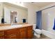 Bathroom with a wood vanity with a single sink and tub/shower combo with a blue curtain at 7019 S Garrison St, Littleton, CO 80128
