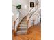 Elegant curved staircase featuring wood railing and plush carpeting, leading to the upper level, with hardwood flooring at 7019 S Garrison St, Littleton, CO 80128