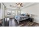 Comfortable bedroom featuring a tray ceiling, dark wood floors, and a large window with blinds at 2853 Yosemite St, Denver, CO 80238