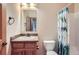 Cozy bathroom with a wood vanity, framed mirror, toilet, and a shower with a decorative curtain at 7971 Larkspur Cir # 219, Frederick, CO 80530