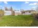 Spacious backyard featuring a covered patio, storage sheds, and a large lawn for outdoor enjoyment at 3055 S Winona Ct, Denver, CO 80236