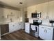 Bright kitchen features white cabinets, stainless steel appliances, and wood-look floors at 9825 W Walker Pl, Littleton, CO 80123