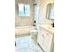 Modern bathroom with marble-look tile, white vanity, sleek fixtures, and a shower-tub combination at 7460 W Bails Ave, Lakewood, CO 80232