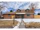 Charming brick home with a well-maintained lawn, complemented by a green door and dormer windows at 9962 W 77Th Ave, Arvada, CO 80005