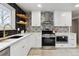 Stylish kitchen with white cabinets, black tile backsplash, and wood shelves at 9962 W 77Th Ave, Arvada, CO 80005