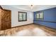 Bedroom with wood floors, blue accent wall, windows and a rustic wood door, creating a cozy and inviting space at 7219 S Brook Forest Rd, Evergreen, CO 80439