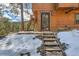 Charming exterior view of the home featuring a wooden door, staircase, and access to the backyard at 7219 S Brook Forest Rd, Evergreen, CO 80439