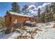 Exterior view of the home with a hot tub, snow-dusted yard, and surrounded by trees and beautiful sky at 7219 S Brook Forest Rd, Evergreen, CO 80439