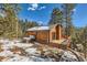 Exterior view of cabin home showcasing the deck, hot tub, wood siding, and serene forest setting at 7219 S Brook Forest Rd, Evergreen, CO 80439