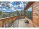 A wooden porch with beautiful views of the surrounding trees and a small bench for relaxation at 7219 S Brook Forest Rd, Evergreen, CO 80439