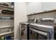 Bright laundry room featuring modern stainless steel washer and dryer, storage shelves, and white cabinets at 5421 S Granby Way, Aurora, CO 80015