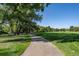 Expansive green space with paved walking path, mature trees, and picnic benches at 7101 W Yale Ave # 3403, Denver, CO 80227