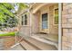 Inviting front entry featuring a covered porch, with brick siding, and a well-manicured landscape at 5960 S Estes St, Littleton, CO 80123