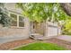 Charming home featuring a brick exterior, front yard with green lawn, trees, and a two-car garage at 5960 S Estes St, Littleton, CO 80123