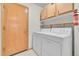 Efficient laundry room with washer, dryer, shelving, and a fire extinguisher for safety and convenience at 5960 S Estes St, Littleton, CO 80123