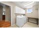 Bright laundry room featuring a washer, dryer, overhead cabinets, and a table at 23961 E Easter Pl, Aurora, CO 80016