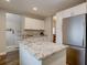 Modern kitchen featuring white cabinets, stainless steel appliances, and a granite countertop island at 124 Elati St, Denver, CO 80223