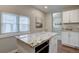 Bright kitchen featuring white cabinets, wood floors, granite counters, and an island with a microwave at 124 Elati St, Denver, CO 80223