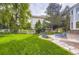 Lush green backyard with stone patio featuring lounge chairs and a white fence at 7866 Witney Pl, Lone Tree, CO 80124