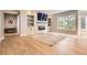 Bright living room features stone fireplace, built-in shelves, large window, and beautiful wood flooring and natural light at 7866 Witney Pl, Lone Tree, CO 80124