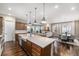 Open kitchen with stainless appliances, center island, flowing to dining and living area with fireplace at 8440 Rush Creek Ave, Littleton, CO 80125